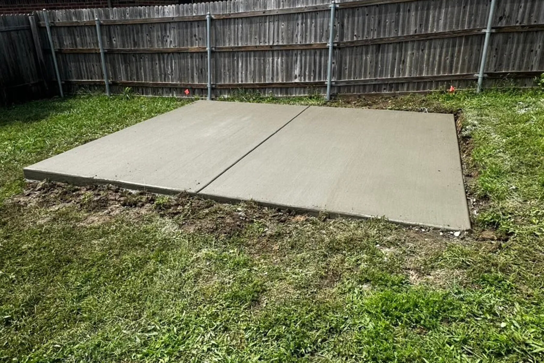 Finished concrete slab poured in a fenced backyard